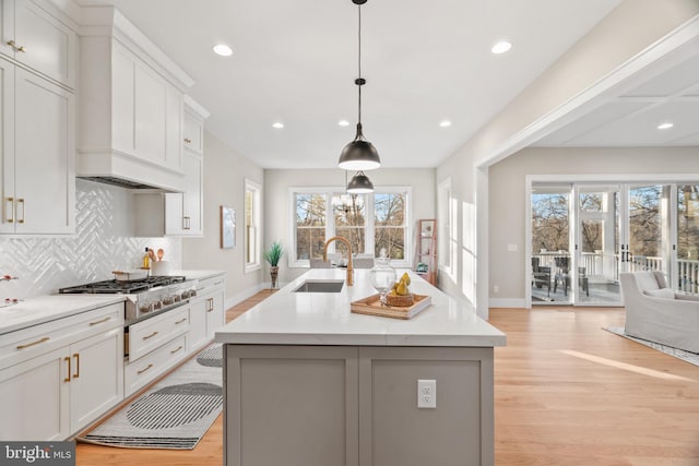 kitchen featuring a kitchen island with sink, sink, a healthy amount of sunlight, and light wood-type flooring