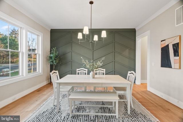 dining area featuring hardwood / wood-style floors, ornamental molding, and an inviting chandelier