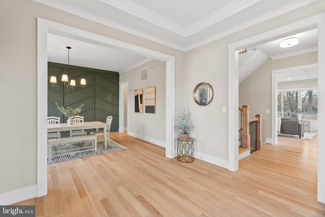 hall with a chandelier, wood-type flooring, and ornamental molding