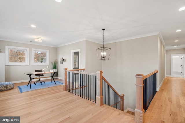 hallway featuring an inviting chandelier, ornamental molding, and light wood-type flooring