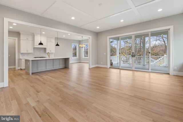 unfurnished living room featuring a notable chandelier and light wood-type flooring