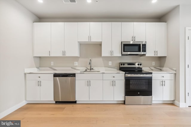 kitchen with light hardwood / wood-style flooring, stainless steel appliances, sink, and white cabinets