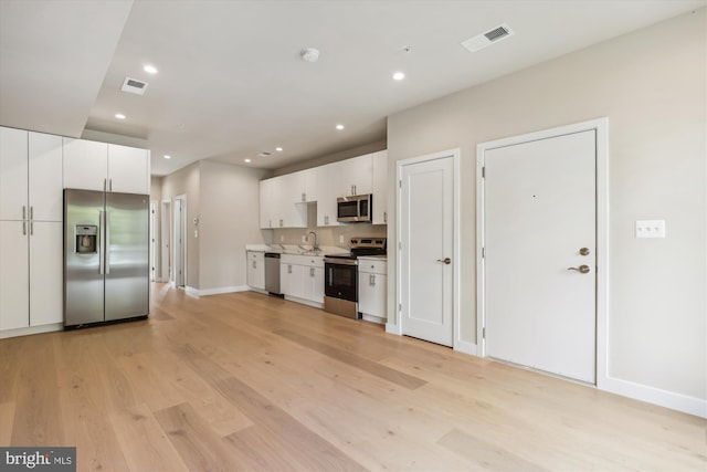 kitchen with light hardwood / wood-style flooring, white cabinets, stainless steel appliances, and sink