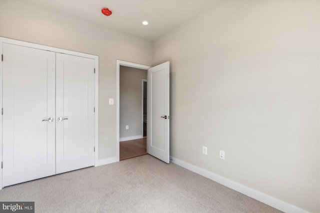 unfurnished bedroom with light colored carpet and a closet