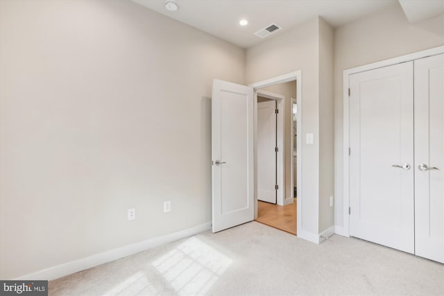 unfurnished bedroom with a closet and light colored carpet