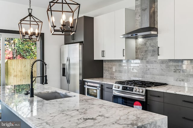 kitchen with white cabinetry, wall chimney exhaust hood, pendant lighting, and appliances with stainless steel finishes