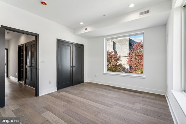 unfurnished bedroom featuring wood-type flooring and two closets