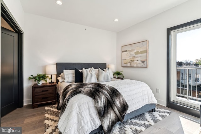 bedroom with hardwood / wood-style floors and access to outside