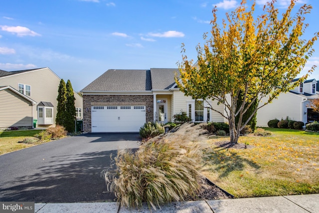 view of front of house with an attached garage, stone siding, a shingled roof, a front lawn, and driveway