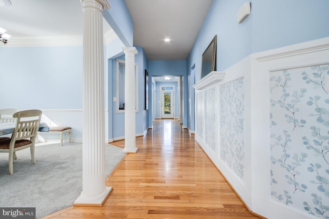 hall featuring crown molding, hardwood / wood-style floors, and decorative columns