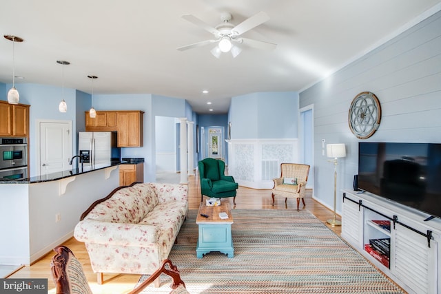 living area featuring baseboards, a ceiling fan, and light wood-style floors