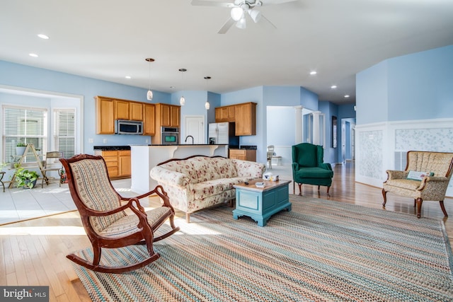 living room with a ceiling fan, recessed lighting, and light wood-type flooring