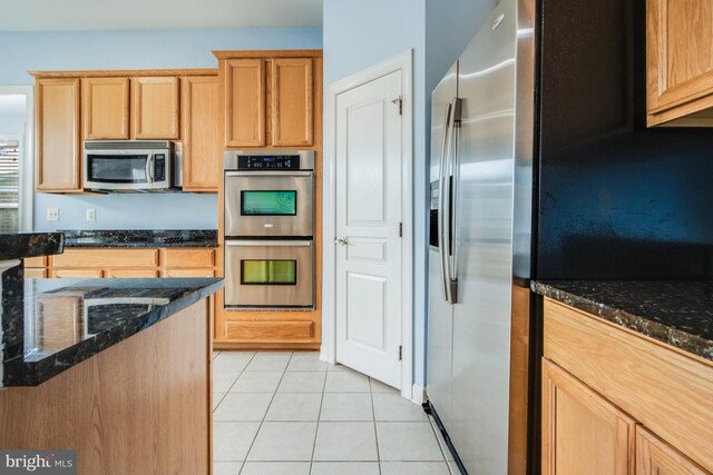 kitchen featuring dark stone countertops, appliances with stainless steel finishes, and light tile patterned floors