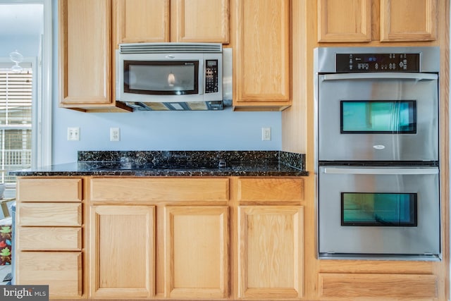kitchen featuring light brown cabinetry, dark stone countertops, and appliances with stainless steel finishes