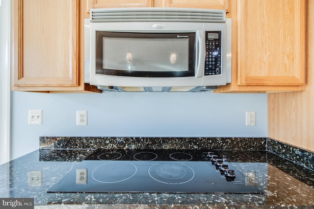 room details with dark stone countertops, black electric cooktop, and light brown cabinets