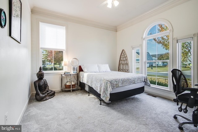 carpeted bedroom with multiple windows, crown molding, and ceiling fan