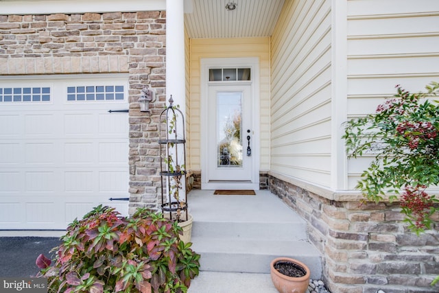 view of exterior entry featuring an attached garage and stone siding