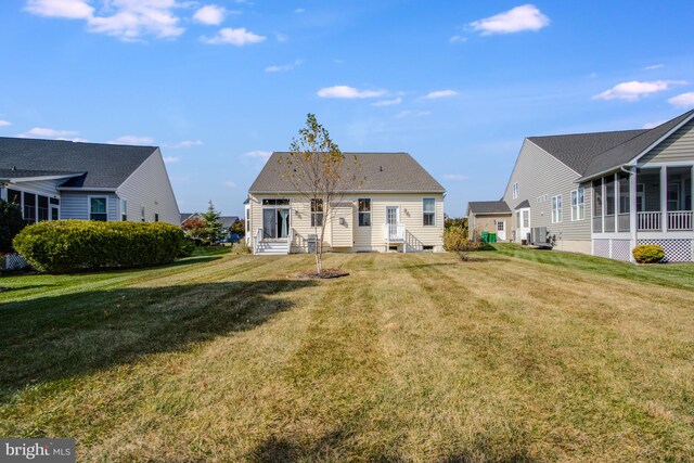 rear view of house featuring cooling unit and a yard