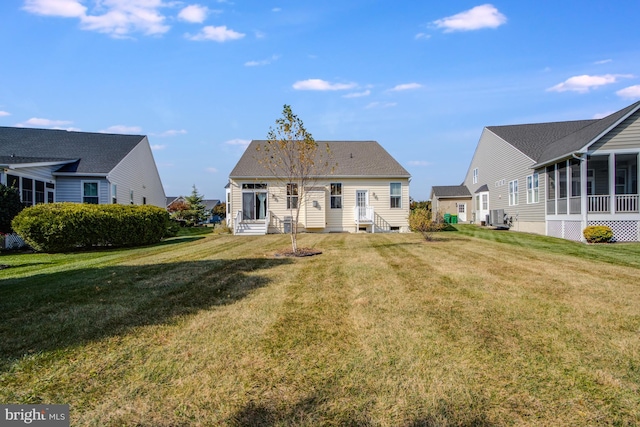 rear view of house featuring a sunroom, a yard, and central AC unit