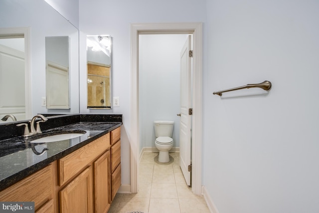 bathroom with toilet, vanity, and tile patterned floors