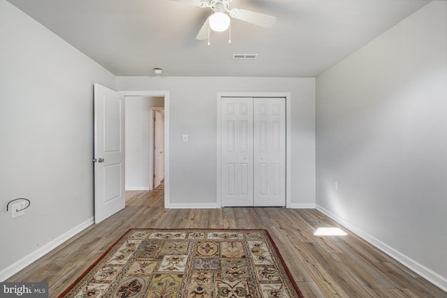 unfurnished bedroom featuring baseboards, a closet, visible vents, and wood finished floors