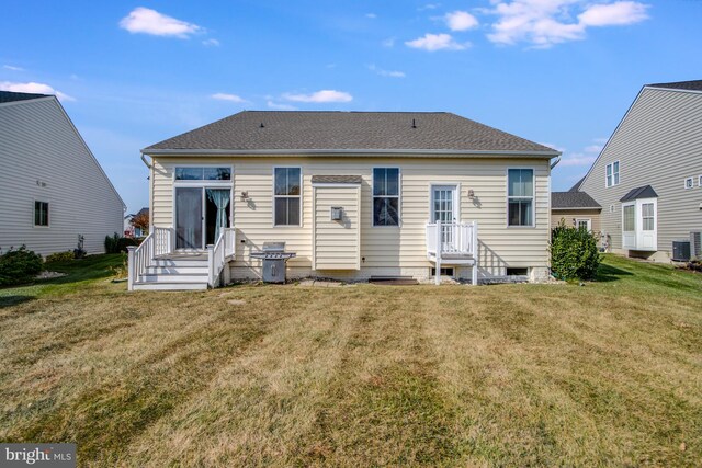 rear view of house featuring cooling unit and a yard