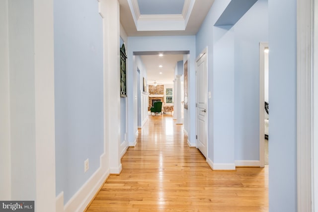 hall featuring baseboards, ornamental molding, and light wood-type flooring
