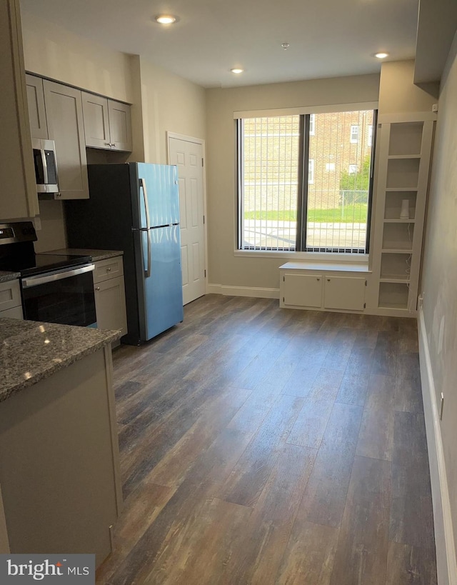 kitchen with light stone counters, appliances with stainless steel finishes, and dark hardwood / wood-style floors