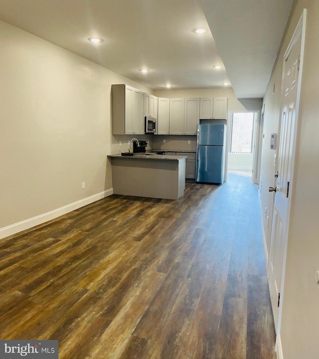 kitchen featuring appliances with stainless steel finishes, kitchen peninsula, dark hardwood / wood-style floors, and sink