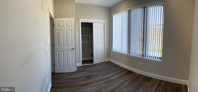 unfurnished bedroom with a closet and dark hardwood / wood-style floors