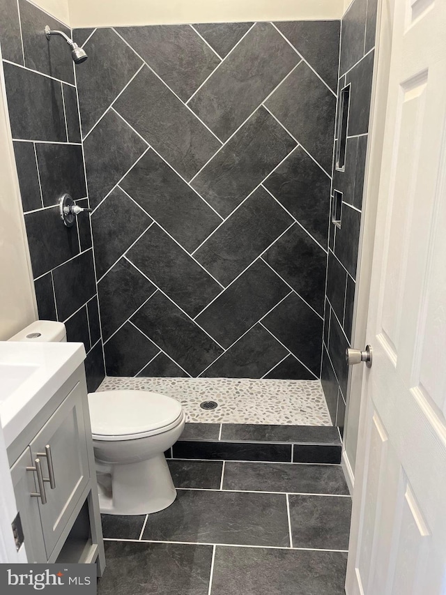 bathroom featuring toilet, vanity, and tiled shower