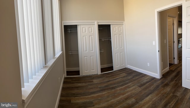 unfurnished bedroom with two closets and dark hardwood / wood-style floors