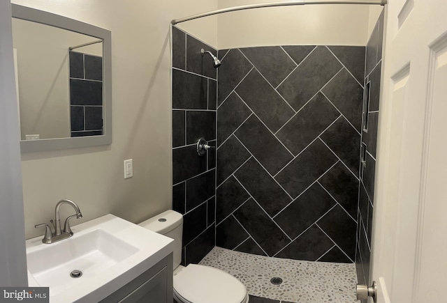 bathroom featuring vanity, toilet, and tiled shower