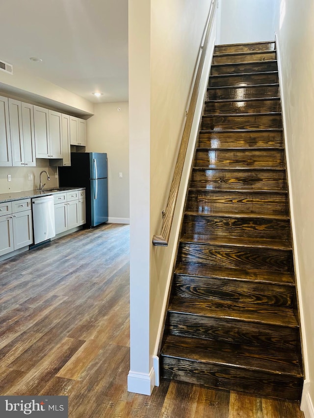 staircase featuring hardwood / wood-style flooring and sink