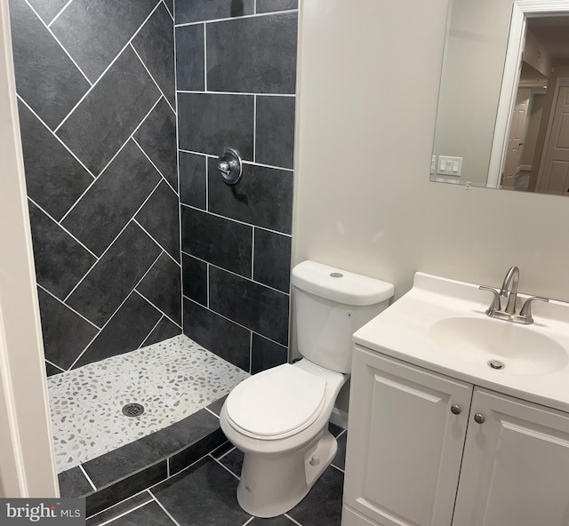 bathroom with vanity, tiled shower, toilet, and tile patterned floors