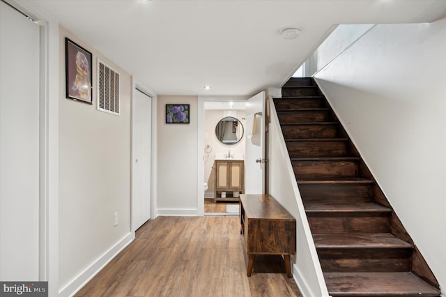 staircase featuring hardwood / wood-style floors and sink