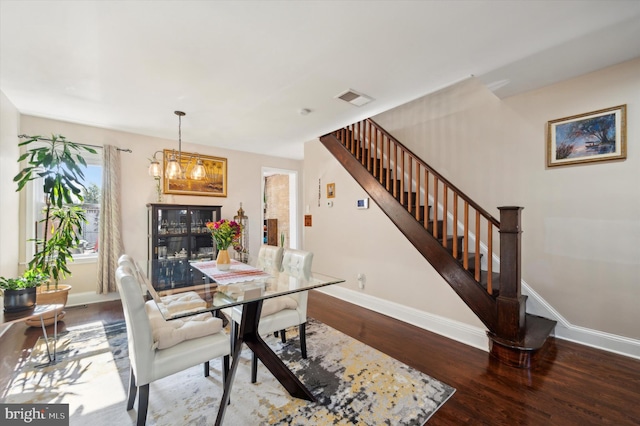 dining area with hardwood / wood-style floors and an inviting chandelier