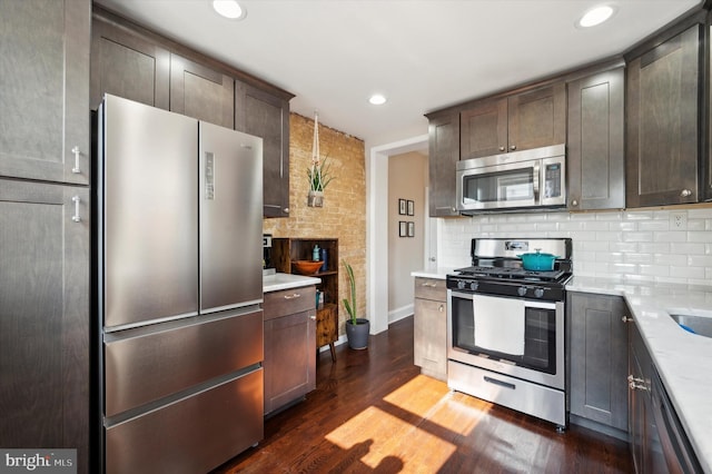 kitchen with pendant lighting, tasteful backsplash, dark brown cabinets, stainless steel appliances, and dark hardwood / wood-style floors