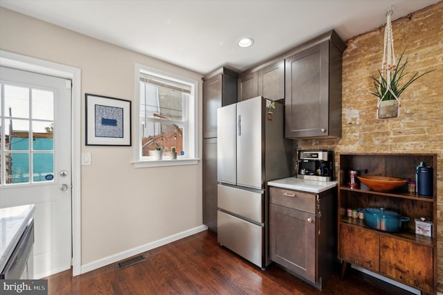 kitchen with dark brown cabinets, decorative backsplash, stainless steel refrigerator, and dark wood-type flooring