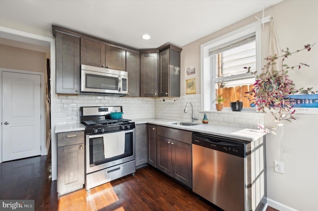 kitchen featuring dark brown cabinetry, appliances with stainless steel finishes, dark wood-type flooring, and sink