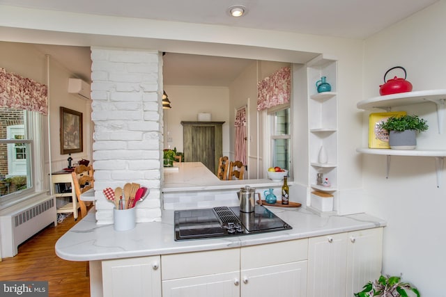 kitchen with open shelves, a wall mounted AC, black electric cooktop, radiator, and white cabinetry