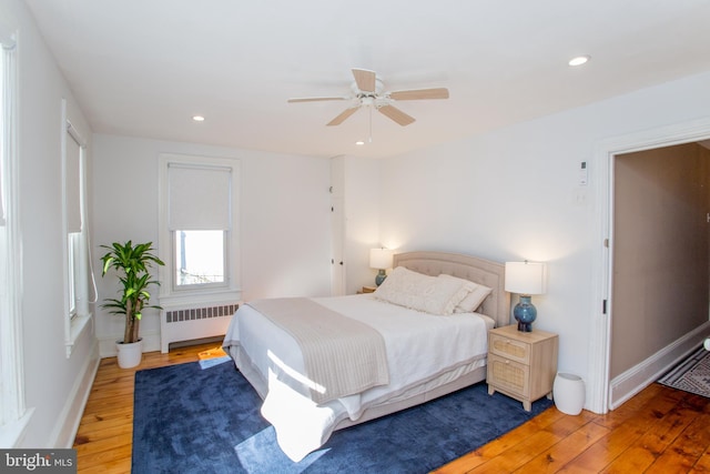 bedroom with hardwood / wood-style floors, baseboards, recessed lighting, and radiator