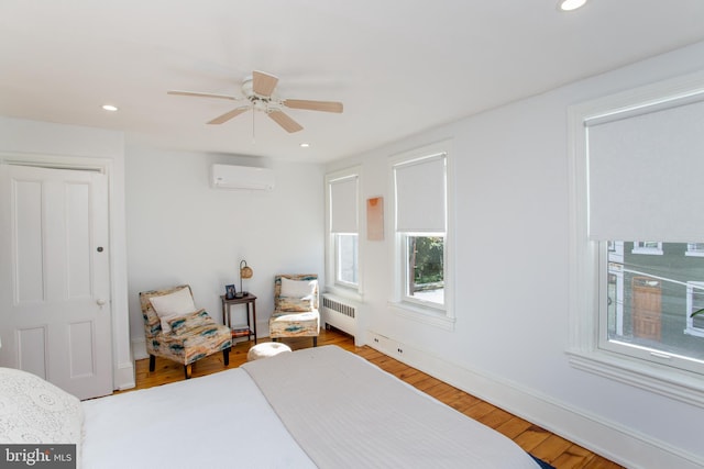 bedroom with recessed lighting, radiator heating unit, wood finished floors, and a wall mounted air conditioner