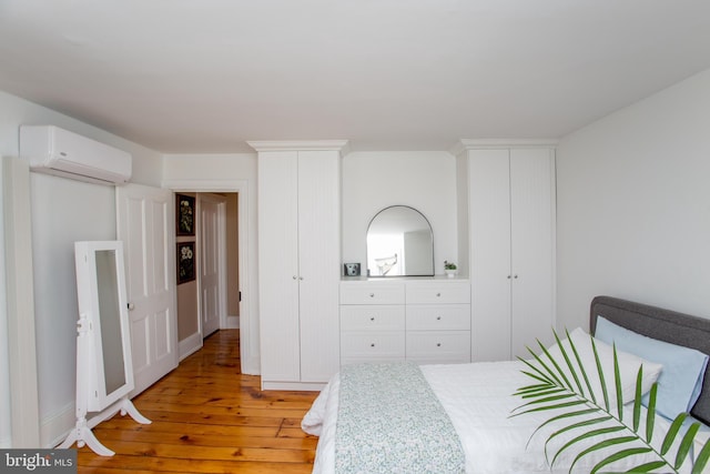 bedroom featuring light wood finished floors and a wall mounted air conditioner