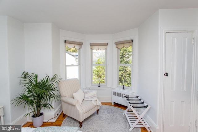 living area with radiator heating unit, baseboards, and wood finished floors