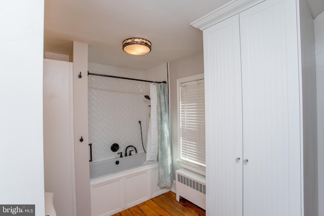 full bathroom with radiator heating unit, shower / bath combo, and wood finished floors