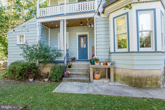 property entrance featuring a lawn and a balcony