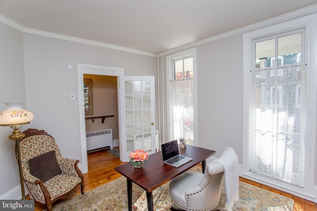 office area with baseboards, light wood-style floors, ornamental molding, and radiator