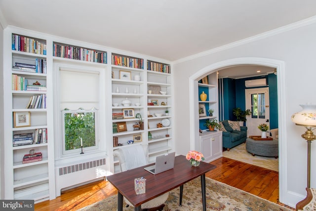 office with an AC wall unit, arched walkways, radiator, hardwood / wood-style flooring, and ornamental molding
