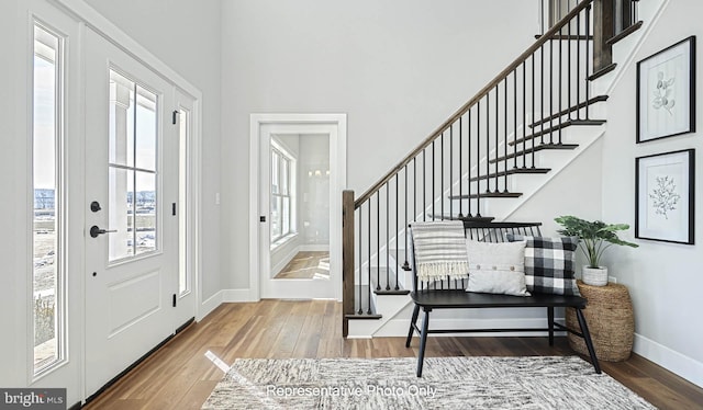 foyer entrance with stairway, a high ceiling, baseboards, and hardwood / wood-style flooring